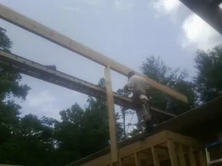 Carpenter setting a ridge beam over a new addition frame — Ice Dam Removal by Roofing Brothers in Boothville