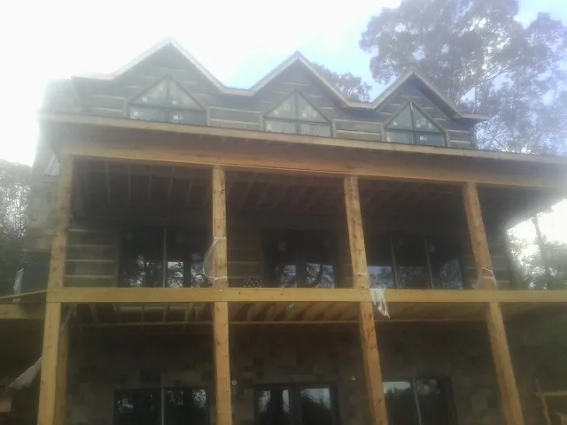 Dormers and porch framing on a large log home under construction — Roof Coating work by our crew in Boothville
