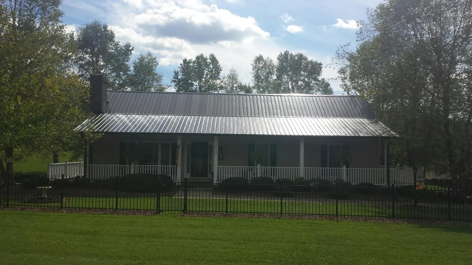 Gray metal roof on a brick ranch with a full width front porch — Gutter Guard Installation work by our crew in Boothville